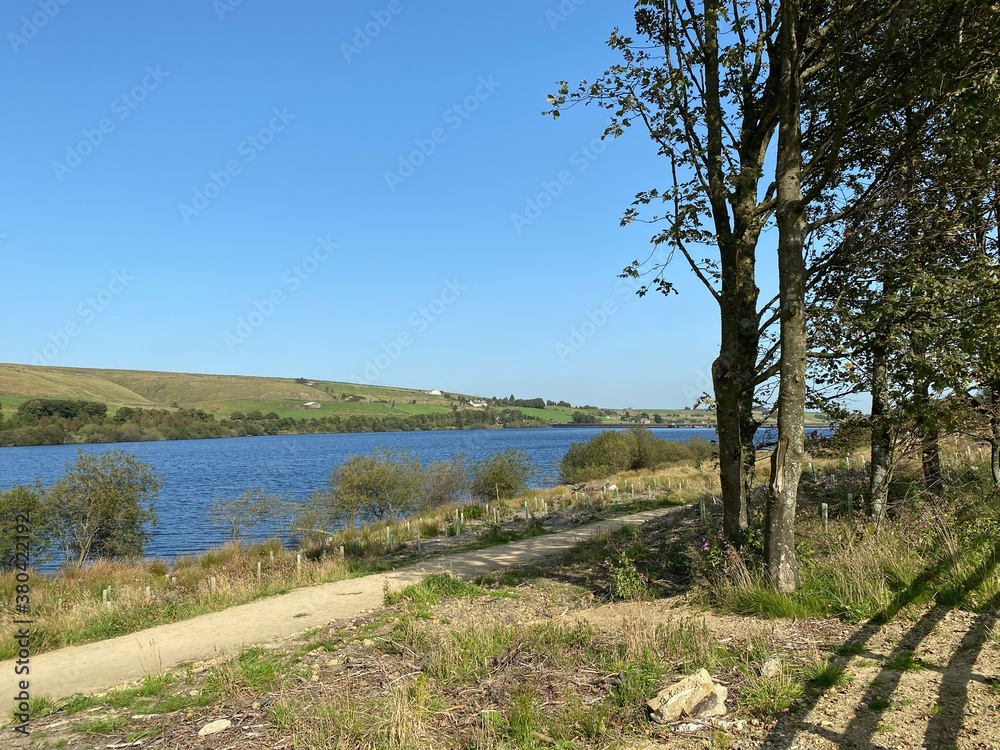 Diagonal view across, Baitings Reservoir, with trees in the foreground, and farms on the horizon near, Ripponden, Sowerby Bridge, UK
