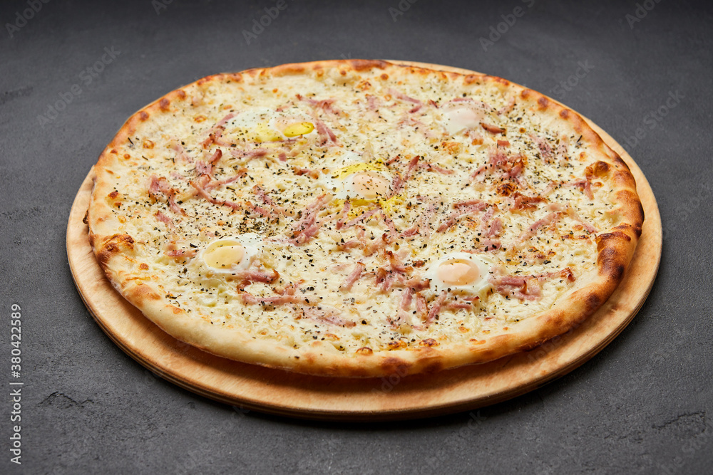 Delicious Italian Pizza Carbonara with Bacon, eggs and mozzarella cheese on dark background Delicious Italian Pizza Carbonara with Bacon, eggs and mozzarella cheese on dark background