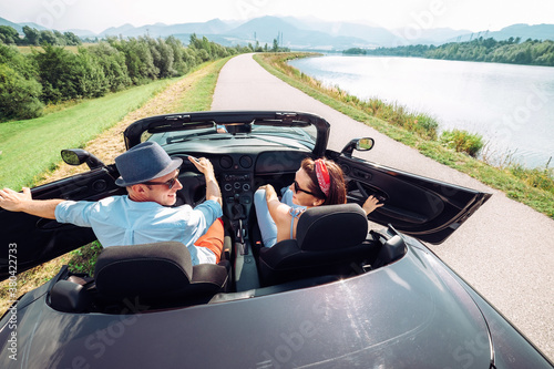 Couple in love getting into the convertable auto and starting a trip. Couple honeymoon or vacation concept image.