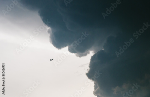 Jet airplane flying overhead with storm cloud imminent photo