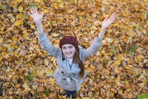 Cheerful young woman on fallen leaves background of autumn forest. Top view.