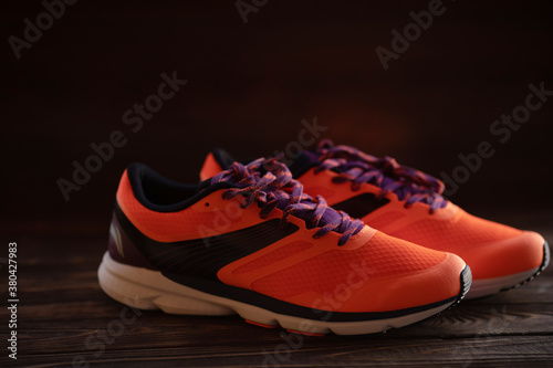 Bright orange sneakers on wooden background with a place for an inscription.