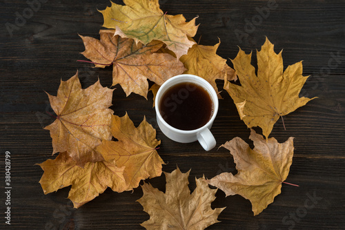 Cup of tea on wooden table, surrounded by autumn leaves. Autumn tea party