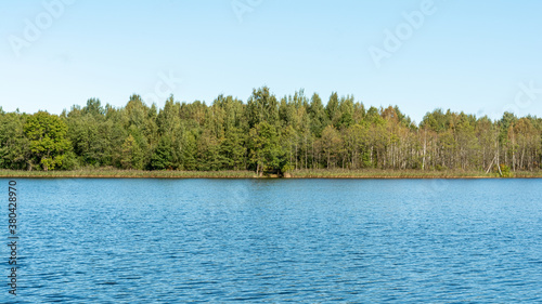 Blue water with small waves horizon forest clear autumn sky. Nature landscape background