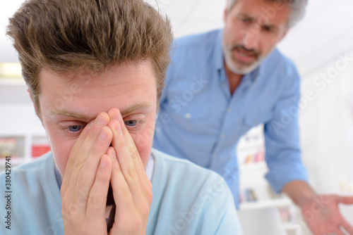 Father reprimanding tearful adolescent son