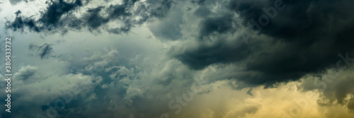 a wide panoramic view of the gloomy stormy dramatic sky with dark cumulus clouds and orange crimson from the bottom side. artistic creative background for sad decoration