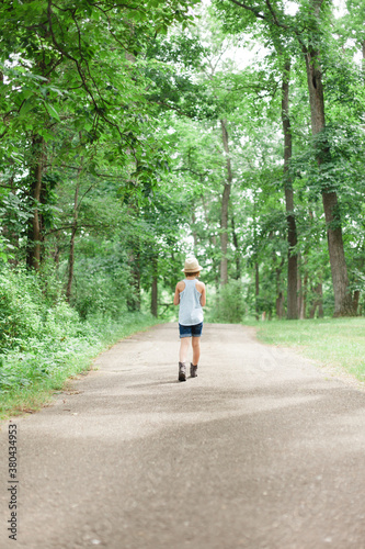 Girl walking along paved trail in the woods photo