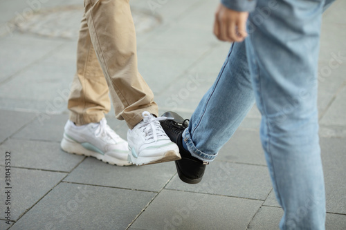 Young people greeting to avoid the spread of coronavirus. Two friends meet, instead of greeting with a hug or handshake, they touch their feet together. Social distance concept. Covid-19.