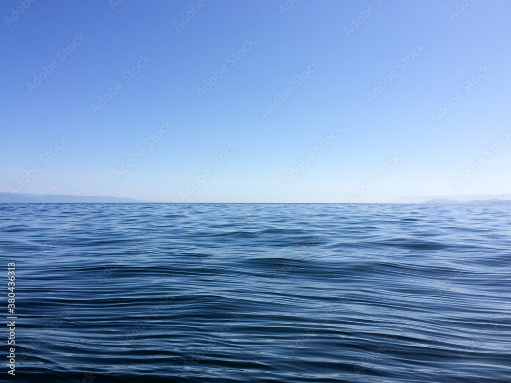 Gentle calm blue ocean waves with horizon and blue sky Gentle calm blue ocean waves with horizon and blue sky