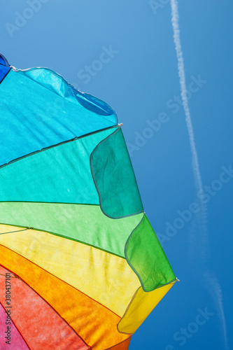 underneath a beach umbrella against a blue sky