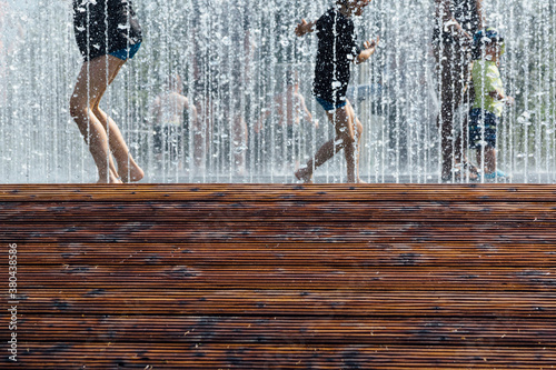 Children playing in water fountain in summer