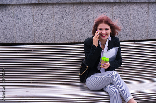 Happy pretty laughing woman with cell phone walking on the street,Clode up portrait of cheerful young lady excited satisfied holding smart phone reading good news outdoor and celebrating in city photo