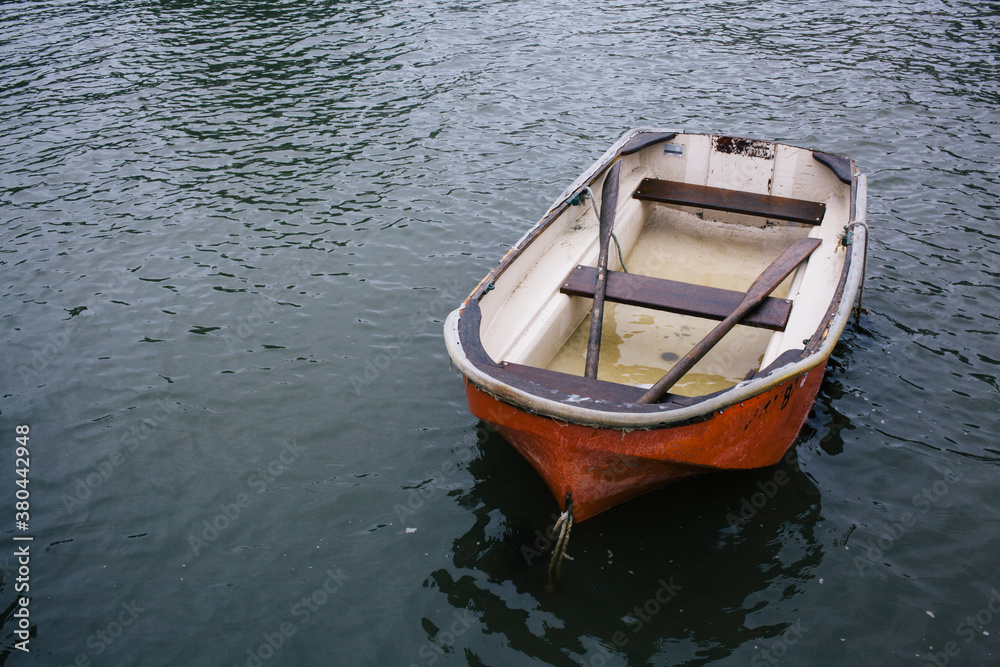 A small red boat with oars in the atlantic ocean. A small red boat with oars in the atlantic ocean.