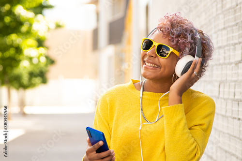 afro american girl with mobile phone and headphones on the street