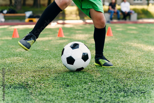Persistent teen soccer player kicking ball on field. Close up feet of footballer kicking ball on green grass. © gorynvd