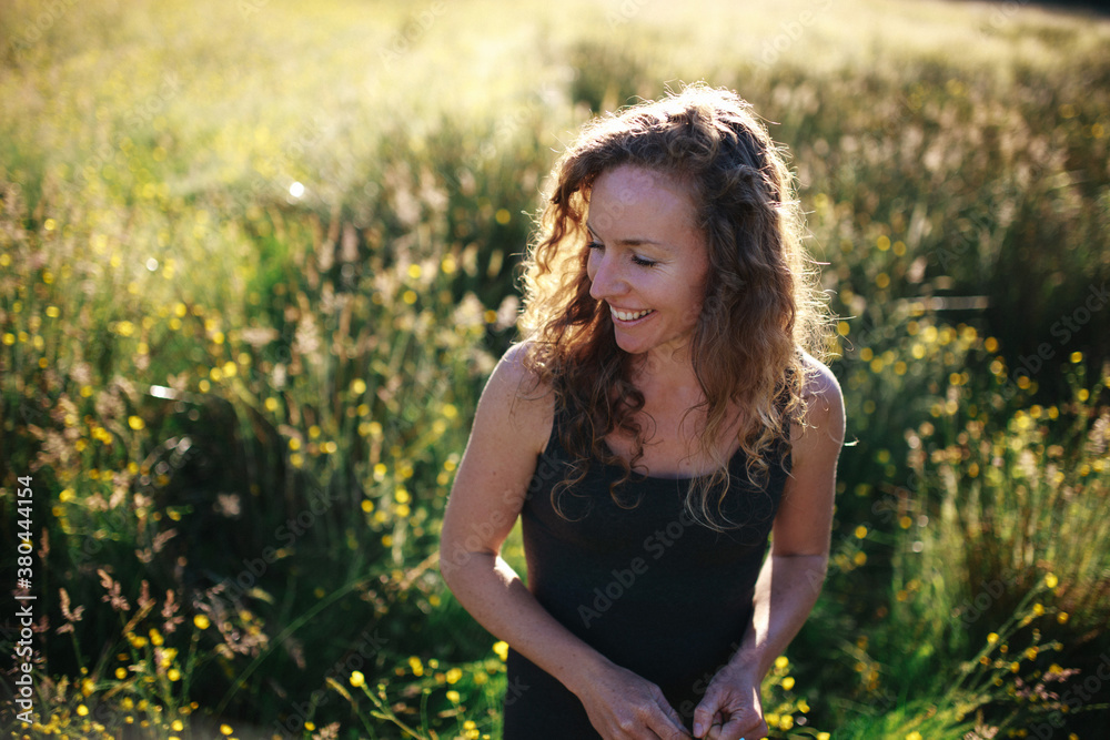 Young woman walking in field in morning light smiling Young woman walking in field in morning light smiling
