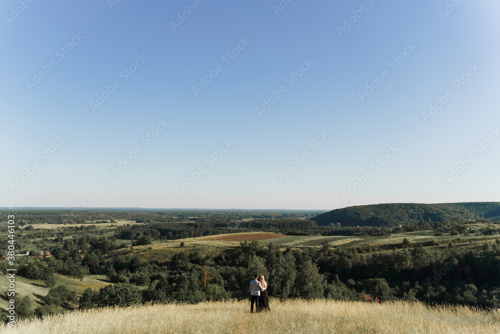 Muslim love story. Mixed couple smiles and hugs on the green hills . Woman weared in hijab looks to her man. Advert for on-line dating agency Muslim love story. Mixed couple smiles and hugs on the green hills . Woman weared in hijab looks to her man. Advert for on-line dating agency