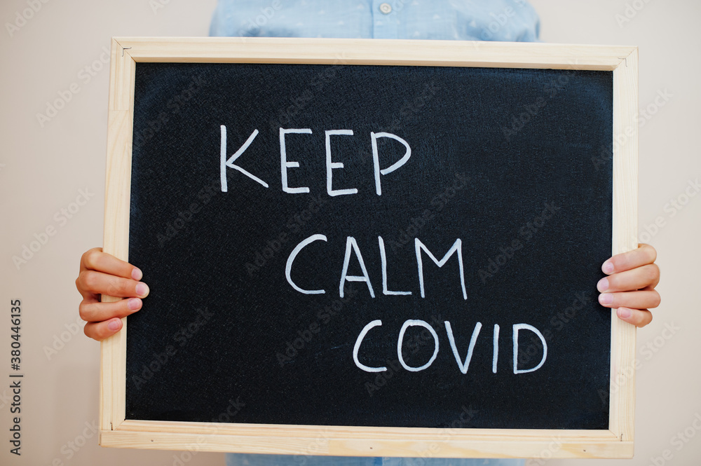 Keep calm covid. Coronavirus concept. Boy hold inscription on the board. Keep calm covid. Coronavirus concept. Boy hold inscription on the board.
