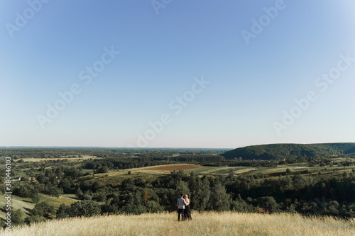 Muslim love story. Mixed couple smiles and hugs on the green hills . Woman weared in hijab looks to her man. Advert for on-line dating agency © Rabizo Anatolii