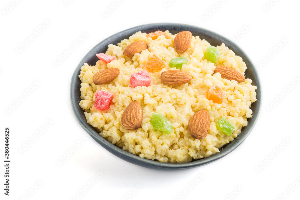 Millet porridge with candied fruits and almonds in blue ceramic bowl isolated on white background. Side view, close up. Millet porridge with candied fruits and almonds in blue ceramic bowl isolated on white background. Side view, close up.
