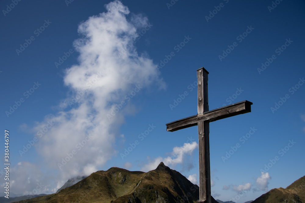 Wooden summit cross with mountains and clouds in the background Wooden summit cross with mountains and clouds in the background