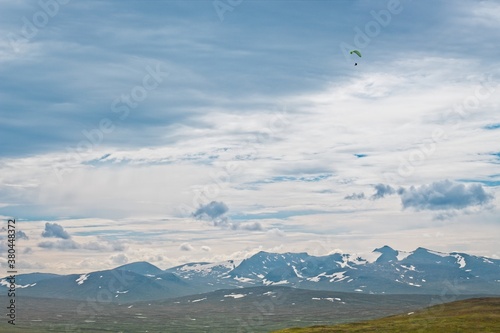 Storulvån (Sweden). Paraglider and a view of the partially snow-capped mountain peaks.