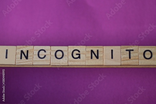  text on gray word incognito in small wooden letters with black font on a lilac background photo