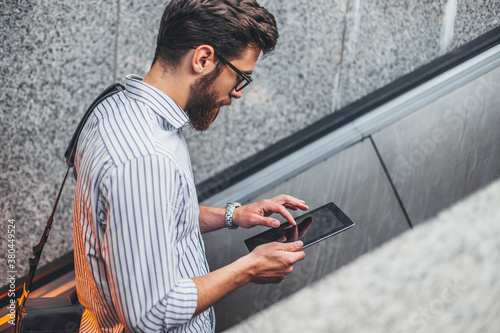 Young businessman standing at a escalator.