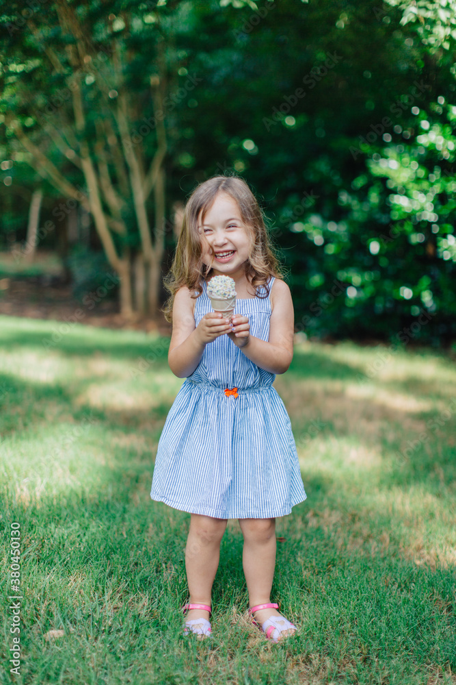 Cute and happy young girl eating ice cream outside
