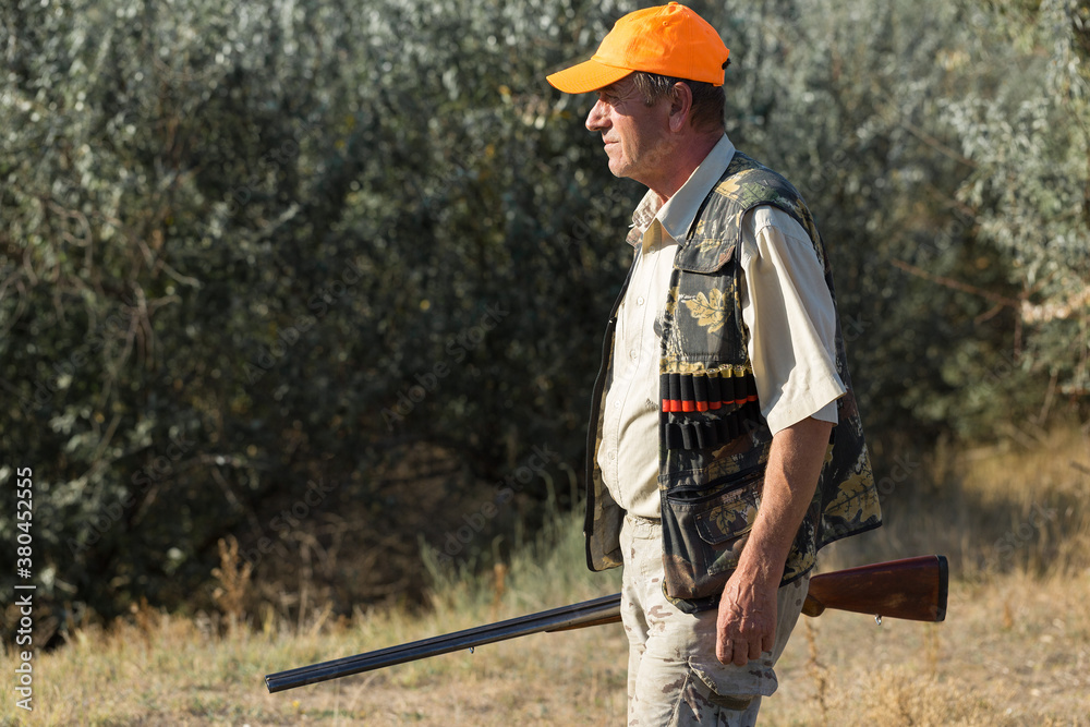 Duck hunter with shotgun walking through a meadow. Duck hunter with shotgun walking through a meadow.