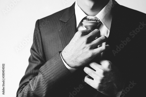 Man on a suit making adjusting his tie.