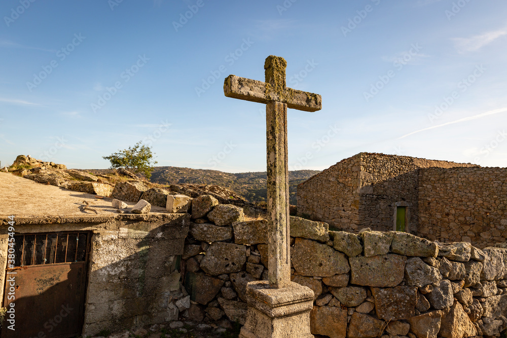 an antique cross made of stone and rustic old houses in Castelo Bom village, municipality of Almeida, Guarda district, Beira Interior, Portugal