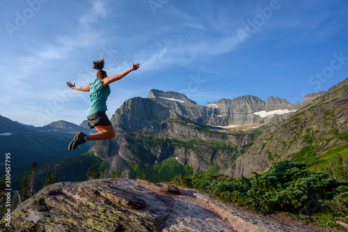 Woman Leaps With View of Grinnell Glacier