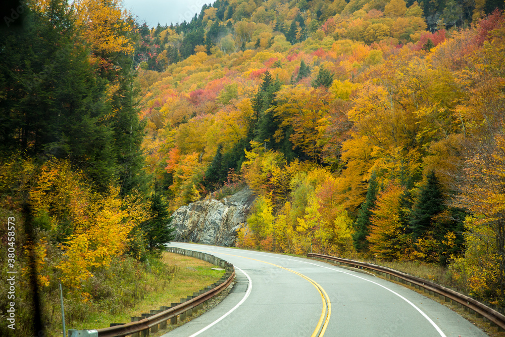 Lost River Road (Hwy 112) winds through a hardwood forest with trees showing peak fall color, west of Lincoln, New Hamnpshire., White Mountain National Forest. Lost River Road (Hwy 112) winds through a hardwood forest with trees showing peak fall color, west of Lincoln, New Hamnpshire., White Mountain National Forest.