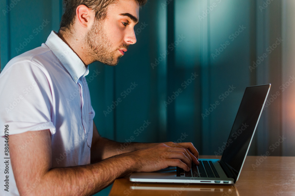 A young man sitting and typing on his laptop in a cafe A young man sitting and typing on his laptop in a cafe