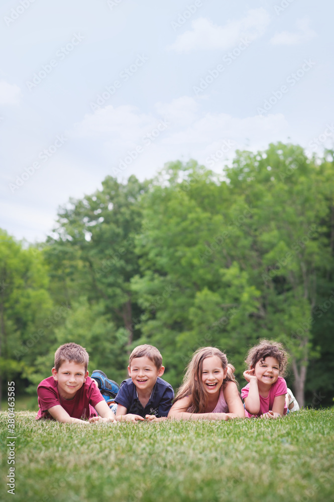 Four happy friends lying on a grassy field smiling Four happy friends lying on a grassy field smiling