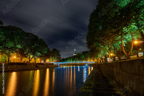 The night view of Aura river in Turku, Finland with a clock tower of cathedral and bridge on a background.