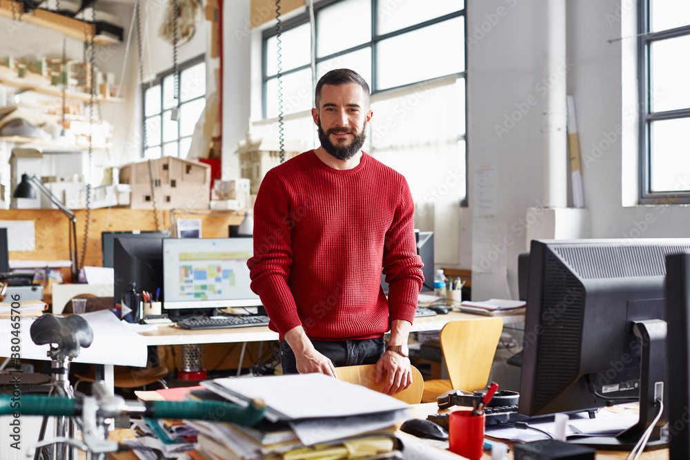Confident Businessman Standing At Office Desk Confident Businessman Standing At Office Desk