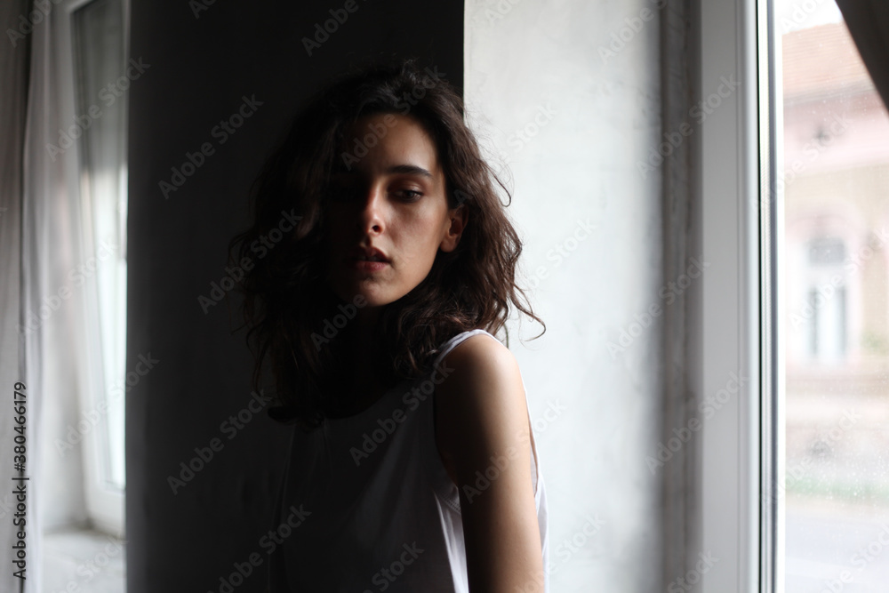 Portrait of a beautiful young woman standing near the window Portrait of a beautiful young woman standing near the window