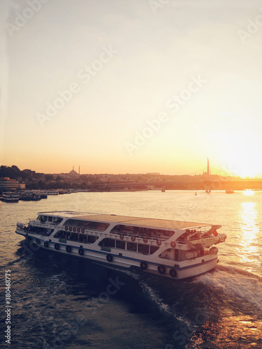 Ferry crossing Golden Horn with silhouette of Eyup Sultan mosque behind at dusk photo