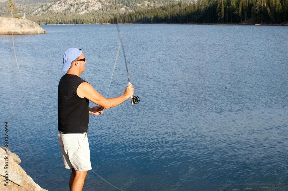 Man fly fishing in a lake during summer Man fly fishing in a lake during summer