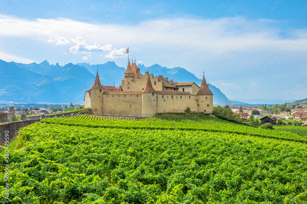 Chateau d'Aigle in Canton Vaud, Switzerland. Aigle Castle overlooking surrounding terraced vineyards and Swiss Alps. Rows of vines growing during the summer.Wine region with popular wine tasting tours