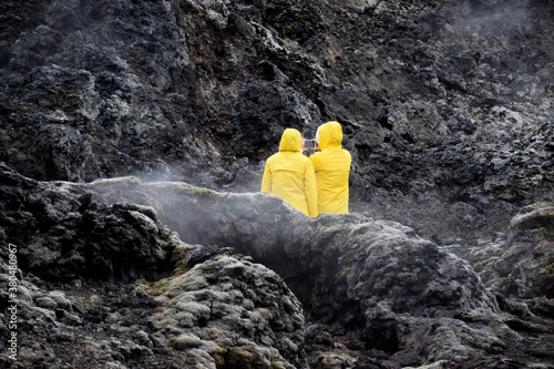 Two people in yellow raincoat in lava field