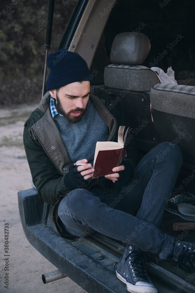 Guy sitting in his bus smoking and reading book Guy sitting in his bus smoking and reading book