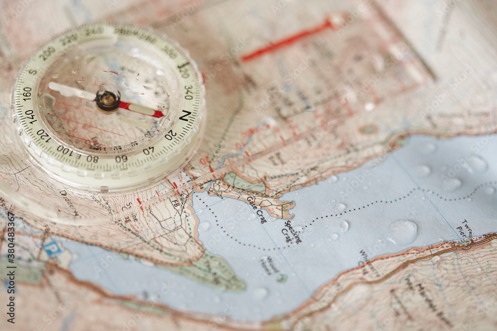 Rain droplets on a waterproof map and compass. Rain droplets on a waterproof map and compass.