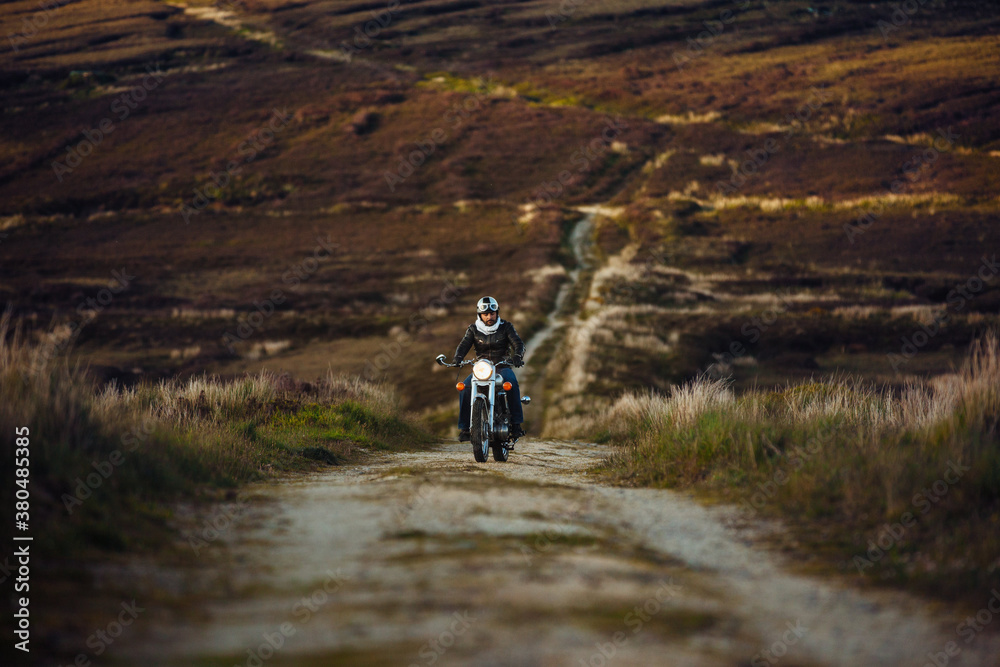 Man riding a classic motorbike on a dirt road Man riding a classic motorbike on a dirt road