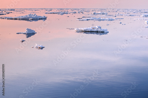 Ice floats in the middle of the sea at sunset photo