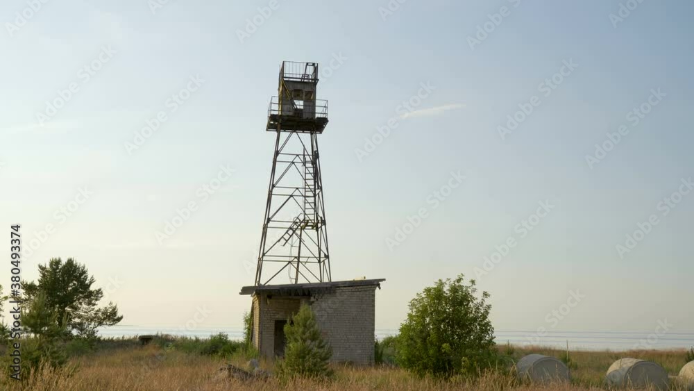 A metal tower on the ground with the small house