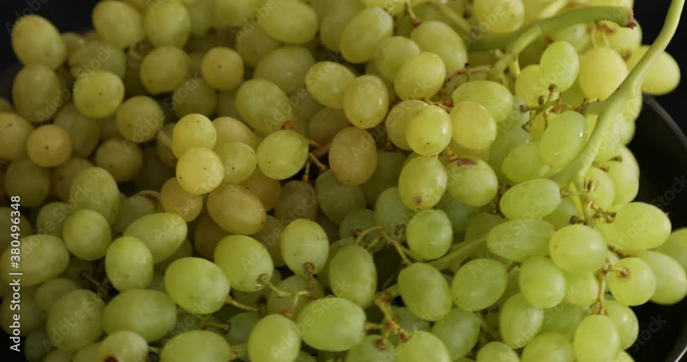 Bunch of white ripe grapes rotating on black background