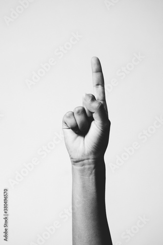 Hand of a woman pointing a finger against a white background.
